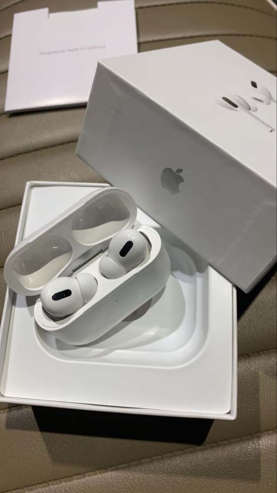 Fones brancos no estojo aberto, com a embalagem ao fundo